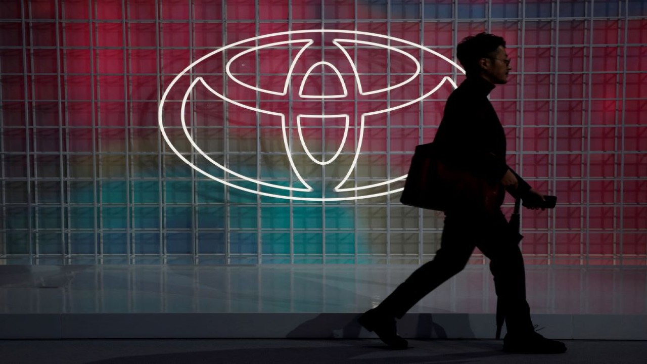 Seorang pejalan kaki sedang berjalan dengan latar belakang logo Toyota. (Foto: Reuters)