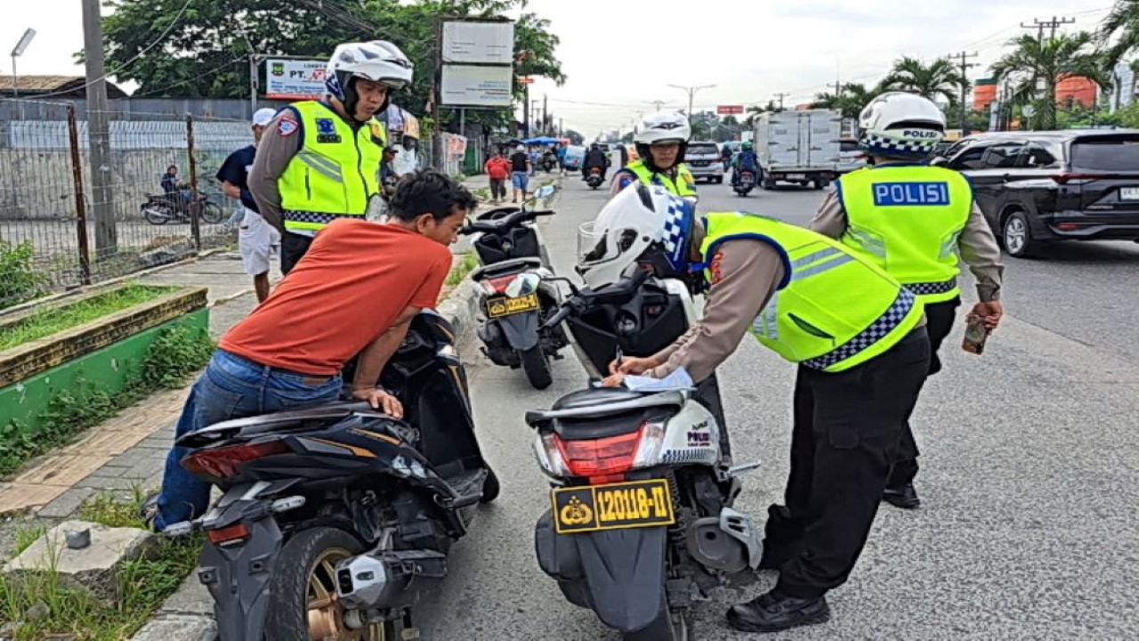 Petugas kepolisian sedang memeriksa dokumen kendaraan pengendara/ist